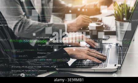 Close-up view of hands typing on a laptop keyboard in a modern office. Coding overlays create a high-tech atmosphere while professionals engage in Stock Photo