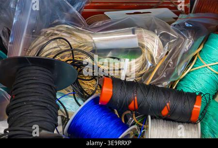 Sewing thread spools pile in different colors and materials inside box Stock Photo