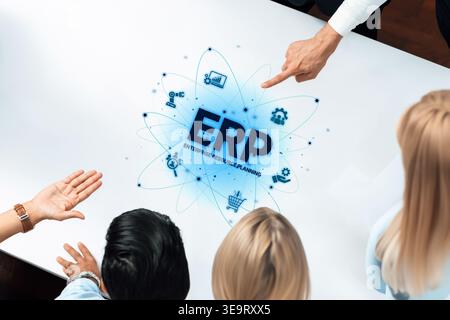 Business team engages in a strategic discussion about Enterprise Resource Planning, showcasing digital graphics on a conference table to enhance Stock Photo