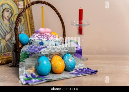 Colorful Easter Cakes And Eggs Arranged On Altar Cloth Near Icon And Candle, Sprinkles Scattered Across Sugar Glaze, Woven Basket Handle Framing Stock Photo