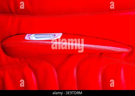 A colorful abstract closeup photo of a red upholstered arm rest on a classic hot-rod automobile. Stock Photo