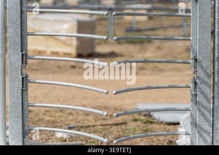 Industrial rotating security gate entrance featuring metal tube bars and heavy duty hinges for pedestrian access control at a high security utility in Stock Photo