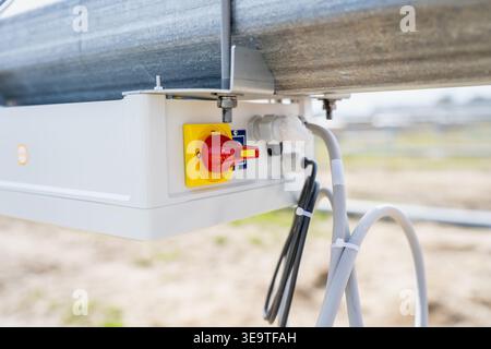 Electrical inverter connection box with red rotary safety switch installed on metal support structure for professional photovoltaic energy production Stock Photo