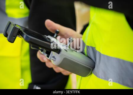 Professional engineer in yellow safety vest holding remote controller for drone inspection of industrial solar farm for renewable energy production an Stock Photo
