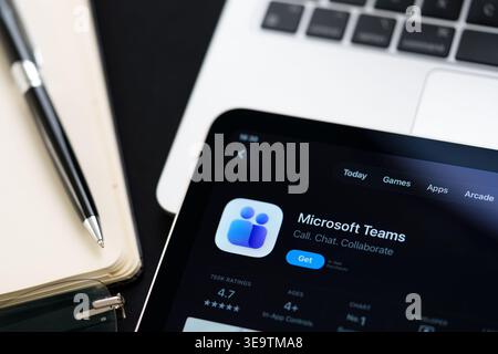 Microsoft Teams app on iPad with Apple Liquid Glass updated look and iOS 26 design on desk beside notebook and laptop. Stafford, United Kingdom, April Stock Photo