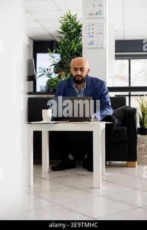Arab man startup business employee typing on laptop, analyzing marketing campaign. Company executive manager planning product sales strategy while working in coworking open space Stock Photo