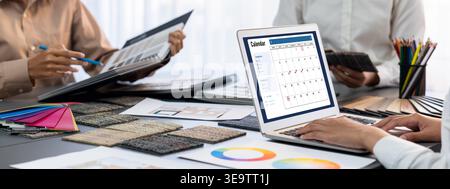 Group of interior architect designer team at table choosing color samples with architecture software on laptop screen. Modern house renovation and Stock Photo
