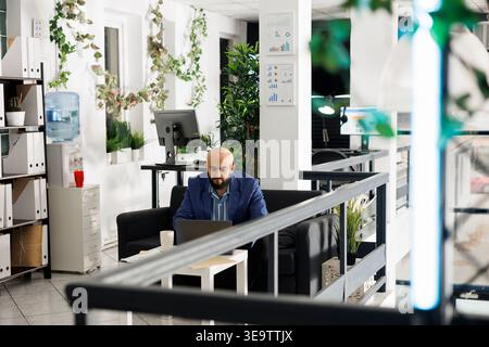 Company arab executive manager analyzing start up strategy on laptop, working in green office. Businessman typing financial report on portable computer in corporate coworking space Stock Photo