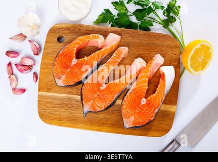 Fresh sliced salmon on wooden cutting board, over white background Stock Photo