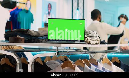 Modern pc with greenscreen template in clothing shop, running blank chroma key display on screen. Shopping center store with isolated mockup copyspace, small business retail market. Stock Photo