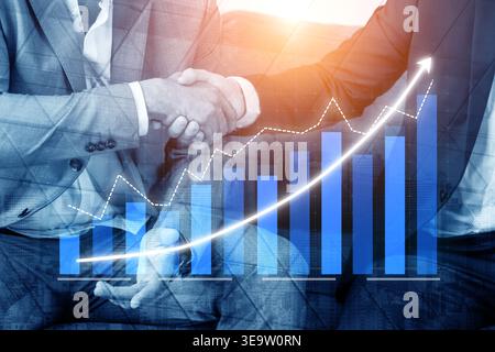 A close-up of a handshake between two business professionals symbolizes partnership and collaboration, combined with financial growth graphs Stock Photo