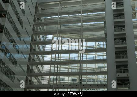 Multi-storey atrium interior featuring stacked walkways, metal railings, and glazed curtain wall in modern office building, The Hague, Netherlands. Stock Photo