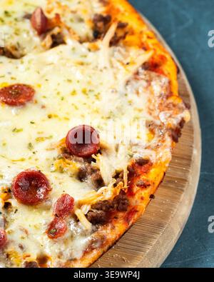 Golden crust, melted cheese, pepperoni, and ground beef. Cheese glistens, herbs sprinkle the top. Pizza rests on a rustic wooden board. Warm, hearty, Stock Photo