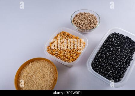 Overhead shot features grains, seeds. Rice in gold bowl, corn kernels, pinto beans, black beans in containers. Clean, bright, promotes healthy eating, Stock Photo