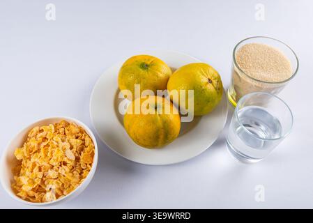 Three oranges on plate with flakes, sugar, and water in minimalist still life setup. Soft diffused light shows food textures. Commercial concept showc Stock Photo