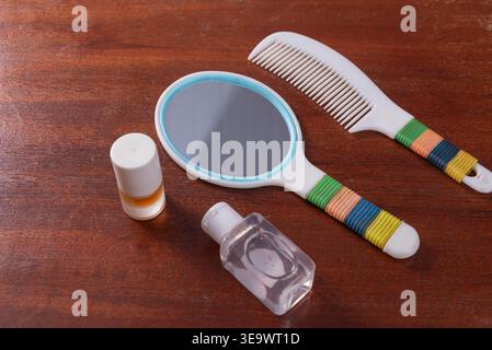 Closeup still life arrangement on wood. Features cosmetics, gel, hand mirror, comb with white, blue, green, orange, yellow. Studio shot, soft lighting Stock Photo