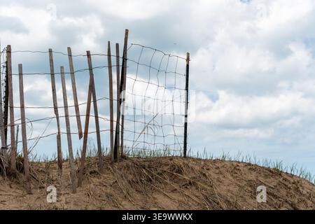 Horizontal photo of a broken fence made of wire mesh on the beach, adding a rugged touch to the coastal landscape Stock Photo