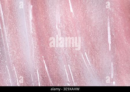Pink glitter spreading on surface forming cosmetic texture background Stock Photo