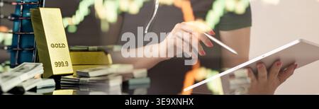 Businesswoman analyzing financial markets on a tablet computer. Overlay with physical gold, US dollars, and forex candlestick graphs. Fintech and inve Stock Photo
