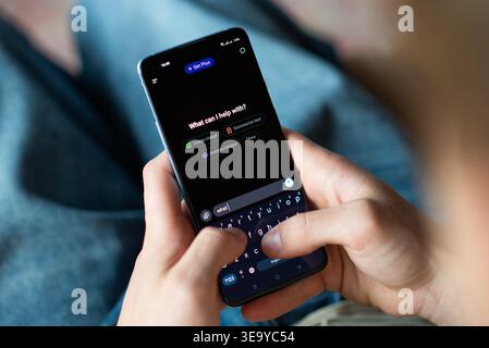 Kyiv, Ukraine - July 16, 2025: Close-up of a person using a smartphone with the ChatGPT app open. The user is typing on the virtual keyboard, a modern Stock Photo