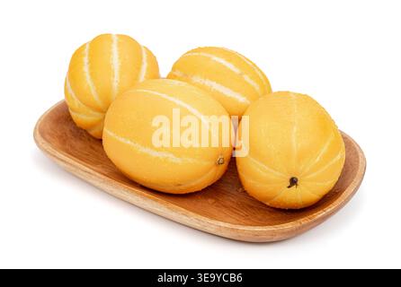 Four fresh Korean yellow melons with water droplets on a wooden tray isolated on white background. Stock Photo