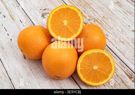 Ripe whole oranges with cross sections on a vintage wooden table, healthy citrus fruit. Stock Photo