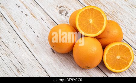 Ripe whole oranges with cross sections on a vintage wooden table, healthy citrus fruit. Stock Photo