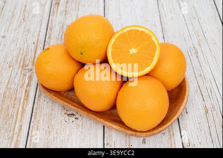 Fresh oranges with water droplets on a wooden tray over white rustic wood background. Stock Photo