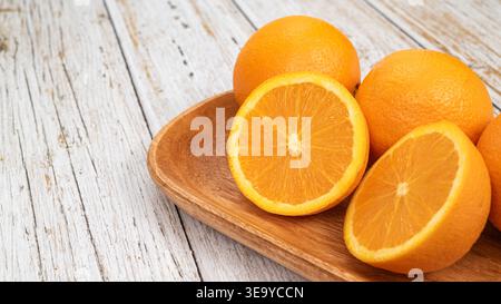 Fresh oranges with water droplets on a wooden tray over white rustic wood background. Stock Photo