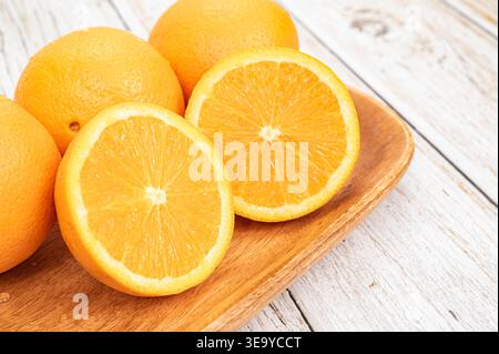 Fresh oranges with water droplets on a wooden tray over white rustic wood background. Stock Photo