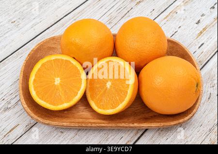 Fresh oranges with water droplets on a wooden tray over white rustic wood background. Stock Photo
