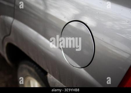 Circular fuel door on a silver vehicle shown in a clean close view with soft reflections.Minimal automotive detail suggests travel energy and everyday Stock Photo
