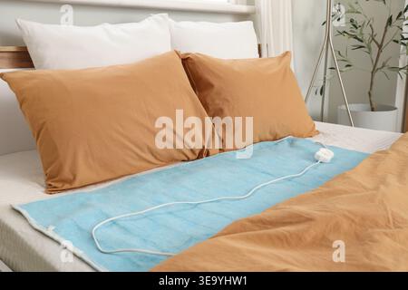 Electric heating pad on bed in room Stock Photo