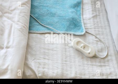 Modern electric heating pad on bed, top view Stock Photo