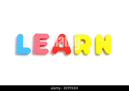 Word LEARN spelled out with five distinct brightly colored magnetic letters in straight line on white Stock Photo
