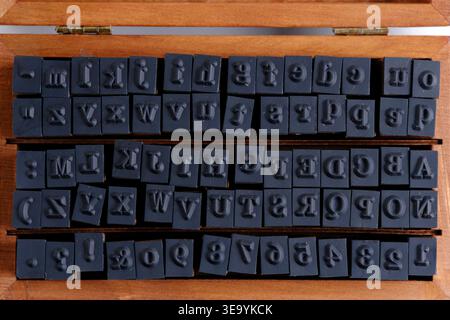 Top down view an open wooden box lid filled with rows assorted alphabet and symbol stamps Stock Photo