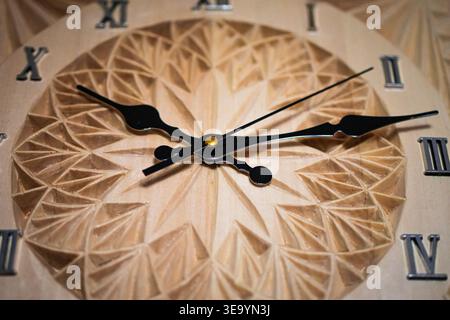 Classic wall clock rendered in warm wood shows intricate relief work and clear roman numerals. The macro angle draws attention to texture balance Stock Photo