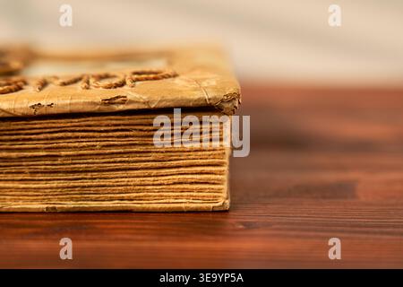 Antique book ambiance. Frayed book edges under warm golden glow. Old pages with worn edges illuminated by soft golden light Stock Photo