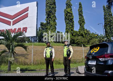 Cikarang, West Java, Indonesia - April 15, 2026: Two security guards stand by the roadside in an industrial area near East Jakarta Industrial Park Stock Photo