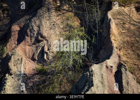 Close view of eroded cliff textures shows rough beige stone and carved ridges. Light slides across gullies and crevices revealing natural patterns Stock Photo