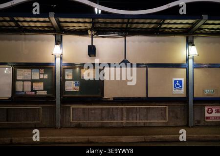 Quiet illuminated station platform at night with information boards and accessibility sign Stock Photo