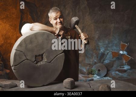 Proud confident prehistoric man holding his innovative invention: the wheel Stock Photo