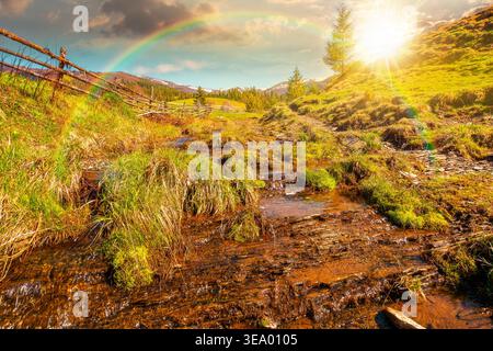sunset over rural scenery in carpathian mountains. simple view of a countryside mountain landscape during springtime. brook near the grassy hills. wea Stock Photo