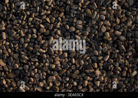 Pebble stone texture background on beach. Natural marine surface with small rocks pattern. Sea coast texture and outdoor nature background concept. Stock Photo