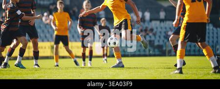 Youth Soccer Match Action. Kids Playing Football and Competing for Ball on Outdoor Grass Field Stock Photo