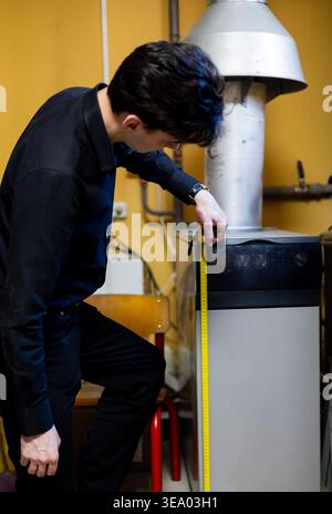 Technician measuring a gas boiler with a tape measure Stock Photo
