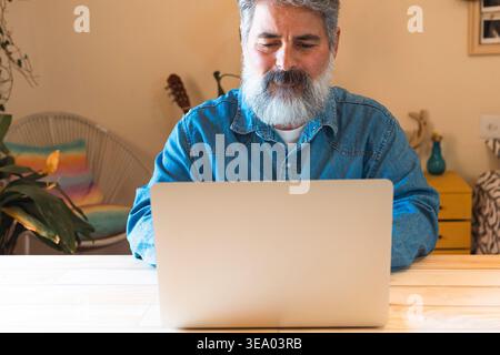 Mature man balancing work and life using laptop from home Stock Photo