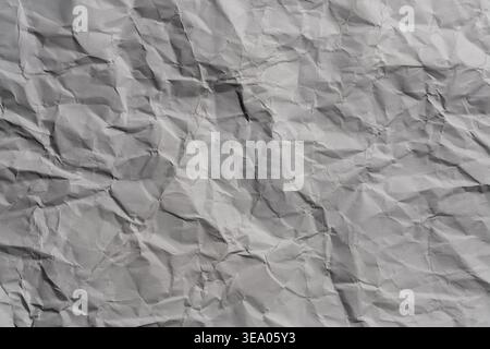 Crumpled grey paper texture with deep creases. Wrinkled grey paper. Messy crumpled surface with shadows and highlights, perfect for grunge backgrounds Stock Photo
