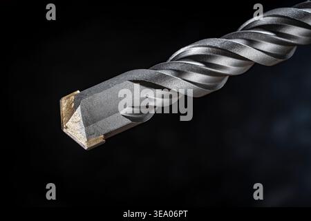 Macro of SDS Plus hammer drill bit for concrete. Close up of a professional masonry drill bit with carbide tip on dark background. Industrial tool for Stock Photo
