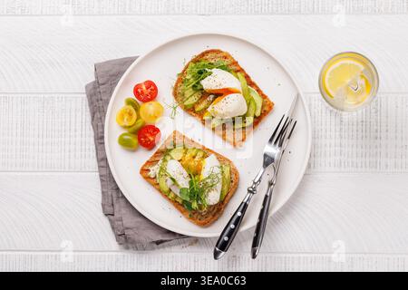 Delicious avocado toasts topped with perfectly cooked poached eggs, served on crispy bread for a healthy and nutritious meal Stock Photo